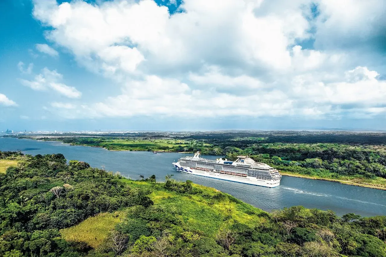 A cruise ship sailing through the green landscape of the Panama Canal